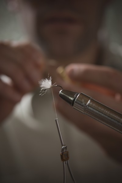 Man repairing fly fishing hook. Photo : Mike Kemp