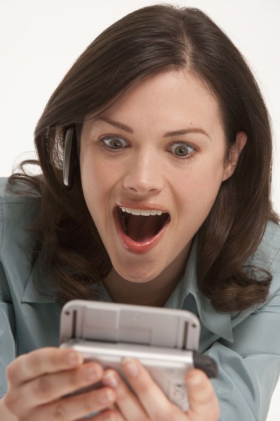 Surprised woman looking at hand held device. Photo : K.Hatt