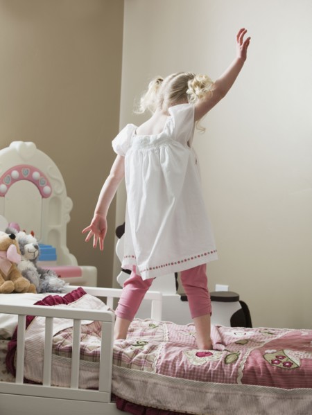 Young girl dancing on her bed. Photo : Mike Kemp