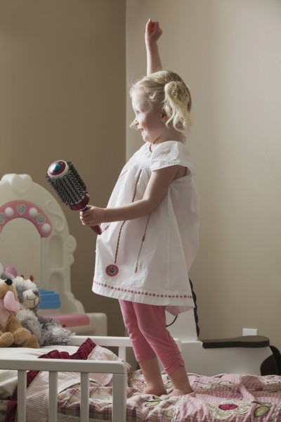 Young girl dancing on her bed. Photo : Mike Kemp