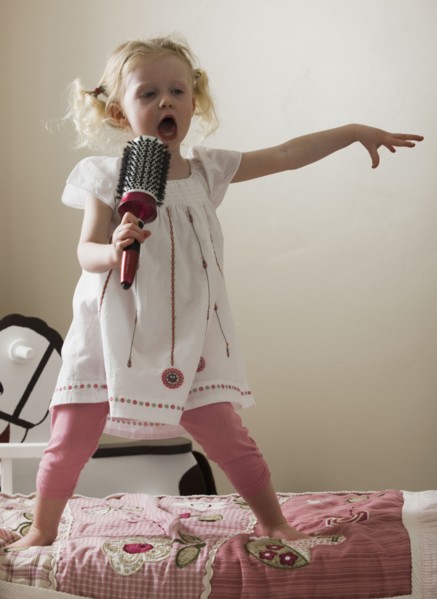 Young girl singing on her bed. Photo : Mike Kemp