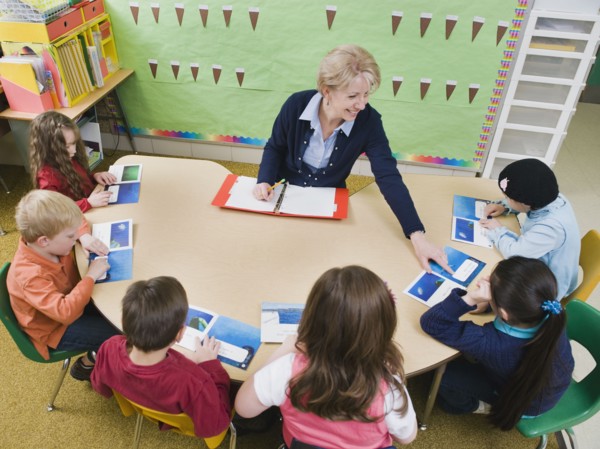 Kindergarten students sitting at table with their teacher.