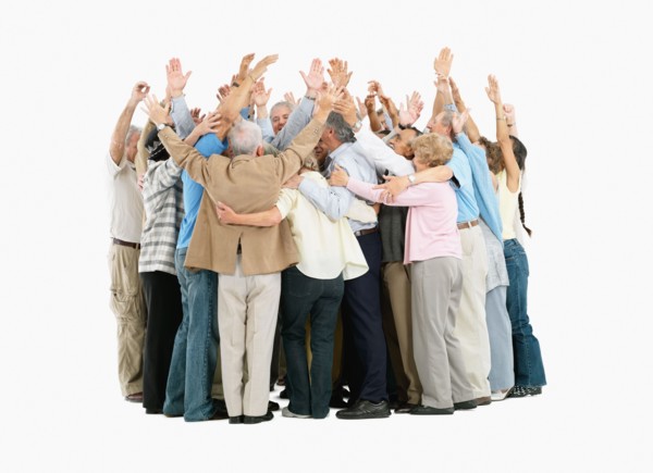 A group of people hugging and raising their arms. Photo : momentimages