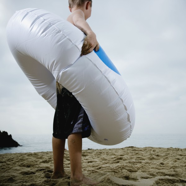 Young boy standing in an inflatable tube at the beach. Photo. FBP