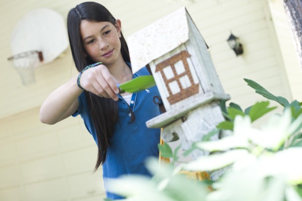 Young girl putting bird seed in birdhouse. Photo : Tim Pannell