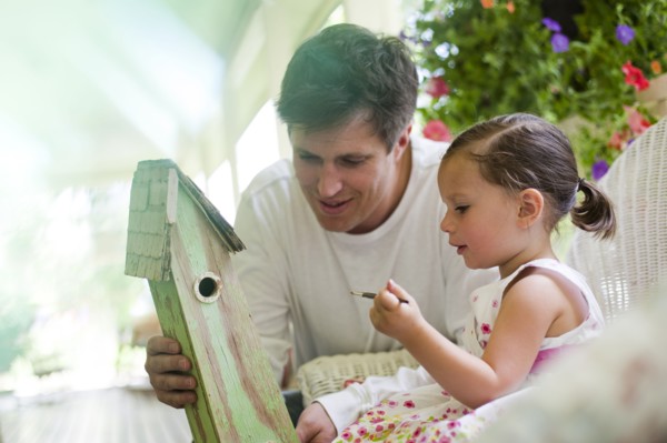 Father helping his daughter paint a birdhouse. Photo. Tim Pannell