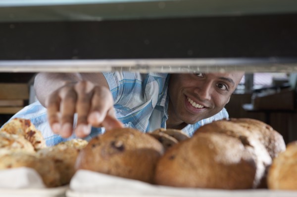 Man reaching for muffin in bakery. Photo : Dan Bannister