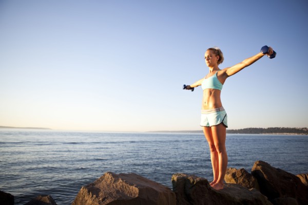 Athletic woman lifting weights outdoors. Photo : Take A Pix Media