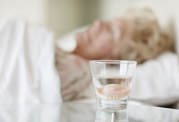 Dentures in a glass of water. Photo. momentimages
