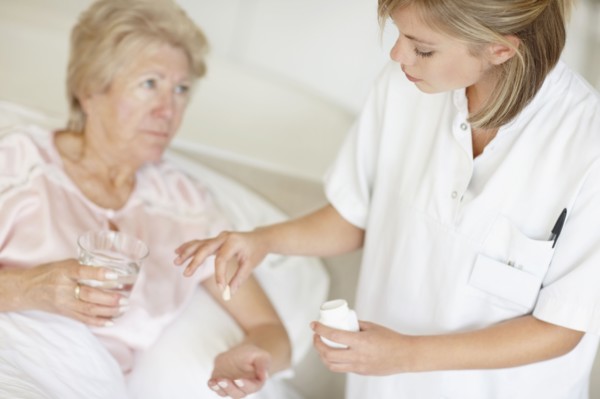 Nurse giving pill to senior woman. Photo. momentimages