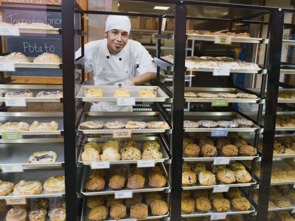 Baker standing behind trays of baked goods.