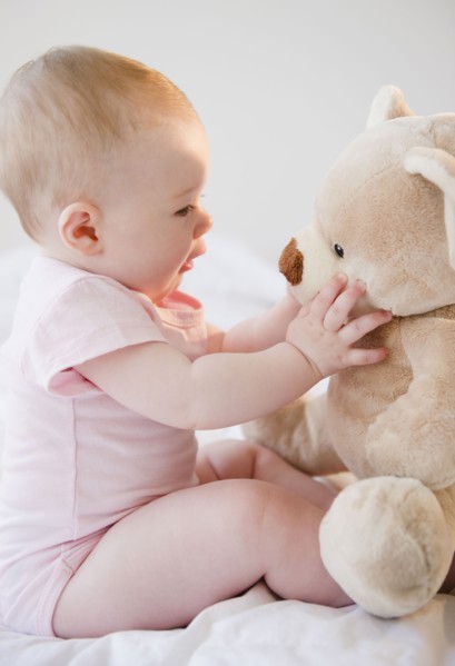 Baby playing with teddy bear. Photo : Jamie Grill