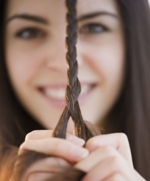 Young woman braiding her hair. Photo. Jamie Grill