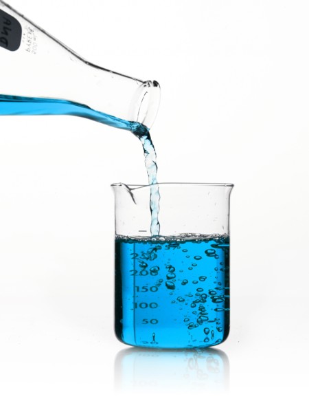 Blue liquid being poured into measuring cup. Photo. David Arky