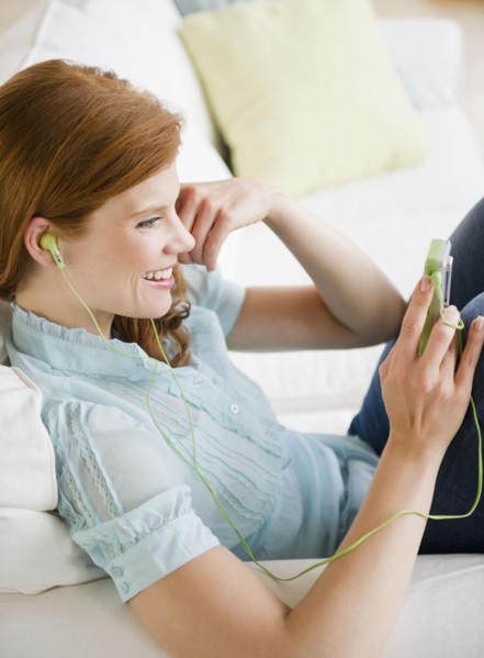 Woman listening to music on Mp3 player. Photo : Jamie Grill