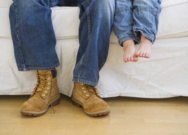 Legs of two people sitting on couch.