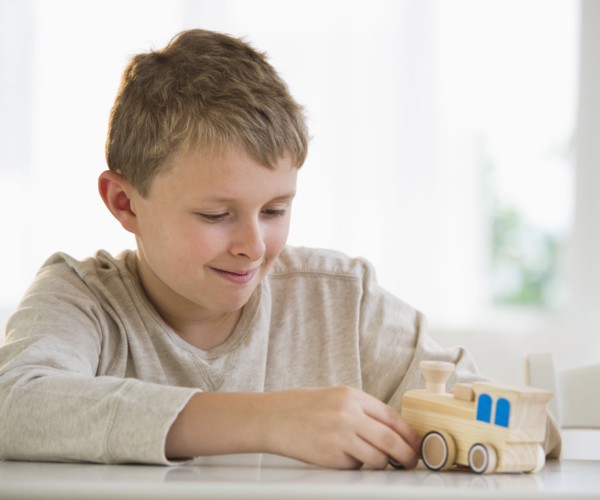 Young boy looking at wooden train.