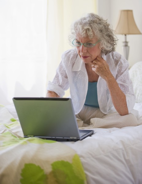 Woman looking at laptop in bedroom. Photo. Daniel Grill