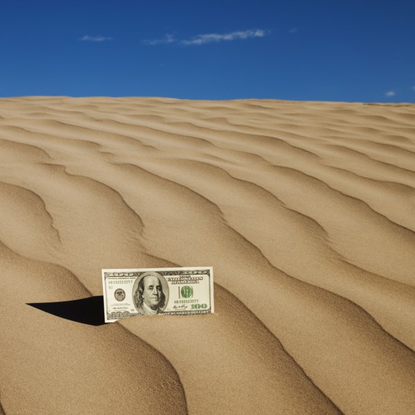 100 dollar bill on sand in desert. Photo. Mike Kemp