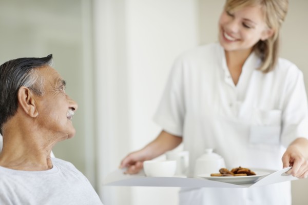 Nurse giving tray of food to patient. Photo : momentimages