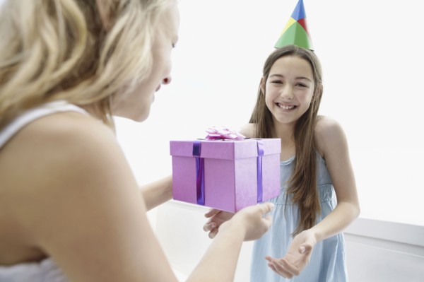 Young girl giving a birthday present to her friend. Photo : momentimages