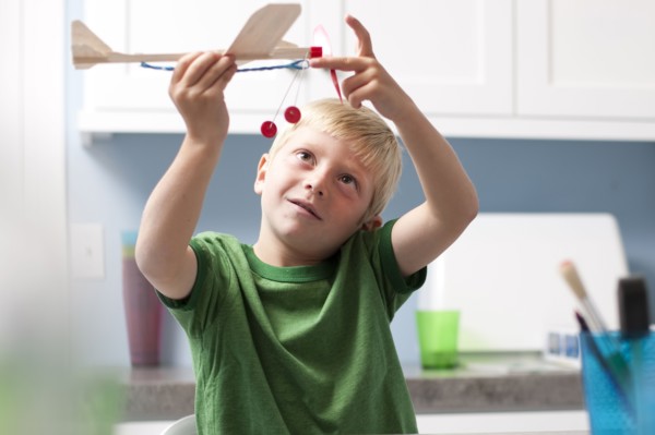 Young boy playing with toy airplane. Photo : Tim Pannell