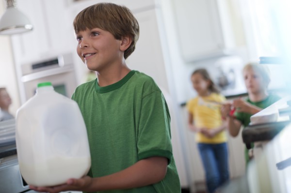 Young boy carrying jug of milk. Photo : Tim Pannell