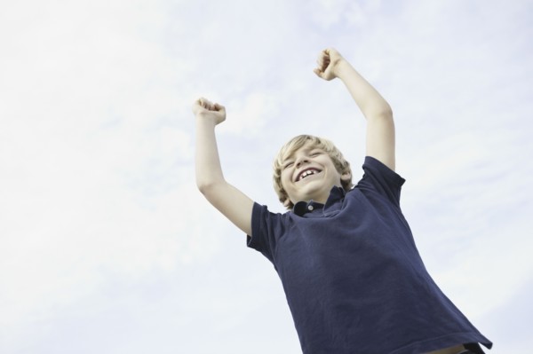 Happy young boy raising his arms in the air. Photo : momentimages