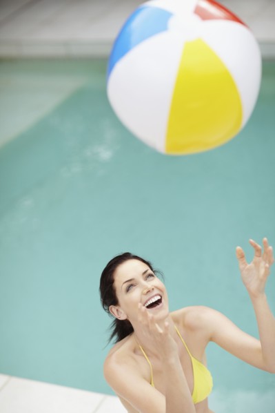 Attractive brunette playing with a beach ball. Photo : momentimages