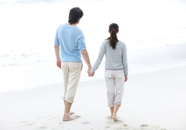 Couple walking barefoot on the beach. Photo : momentimages