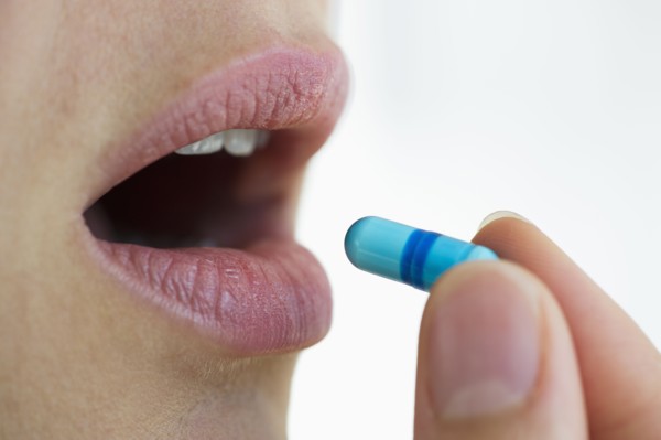 Woman putting capsule in her mouth.