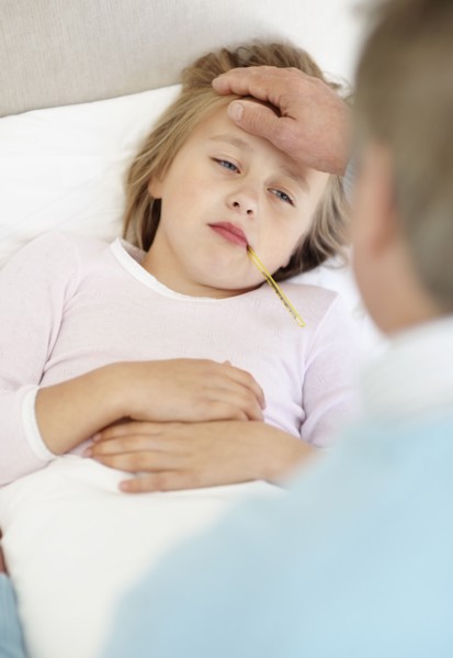 Grandfather tending granddaughter (10-11) lying in bed with thermometer in mouth. Photo :
