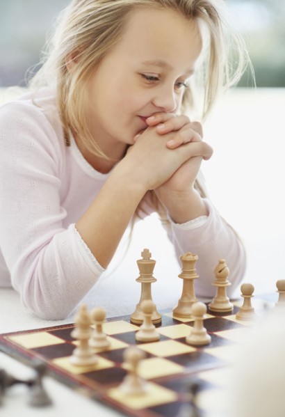 Girl (10-11) playing chess. Photo : Momentimages