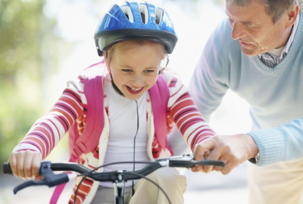 Grandfather helping granddaughter (10-11) riding bike. Photo : Momentimages