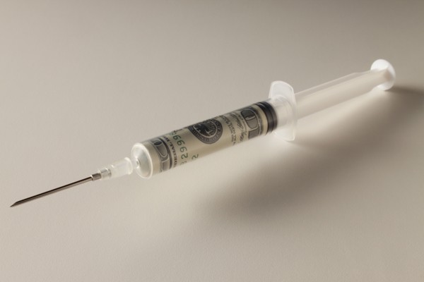 Studio shot of syringe with dollar banknote. Photo : Mike Kemp