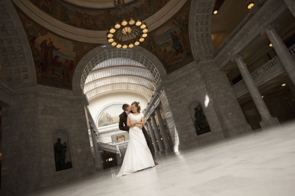 Bride and groom embracing under arch. Photo : FBP