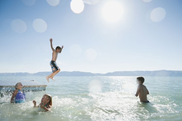 Kids (6-7,8-9,10-11,12-13) playing on raft on lake.