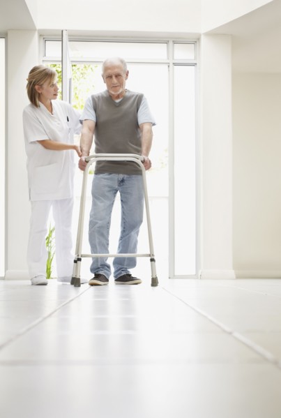 Nurse assisting patient in corridor of clinic. Photo : Momentimages