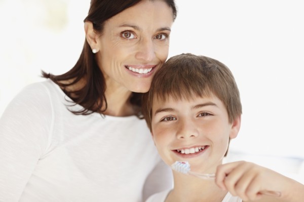 Mother embracing son (12-13)  while he is brushing teeth. Photo : Momentimages