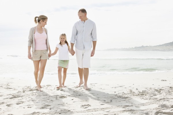 Girl (10-11) playing on beach with parents. Photo : Momentimages
