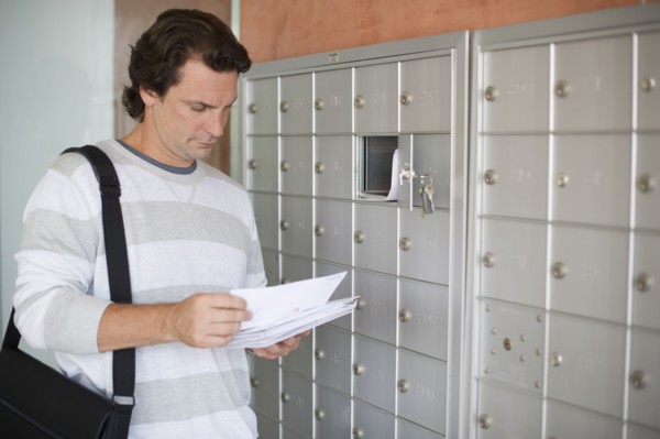 Man standing next to mailboxes and checking post.