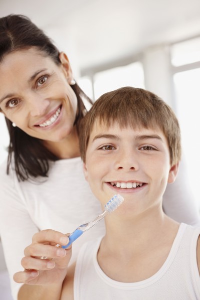 Mother embracing son (12-13) while he is brushing teeth. Photo : Momentimages