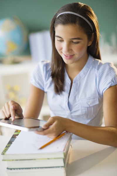 Schoolgirl (12-13) using digital tablet.