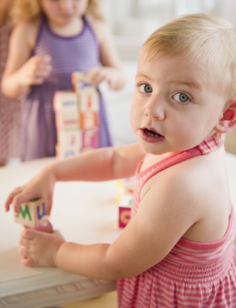 Girls (18-23 months, 4-5) playing with blocks and looking at camera. Photo : Jamie Grill