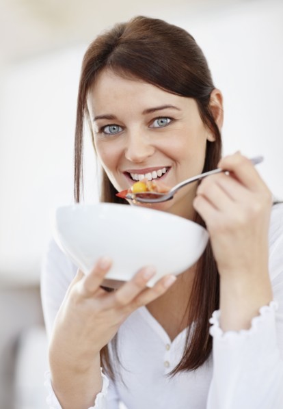 Portrait of mid adult woman eating from bowl. Photo : Momentimages