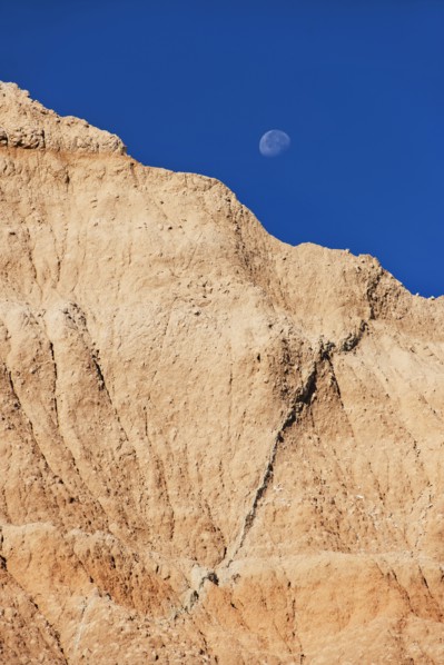 USA, South Dakota, Mountain against blue sky with moon in Badlands National Park.