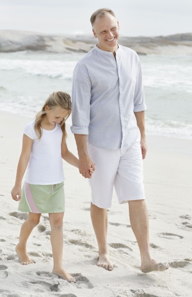 Girl (10-11) playing on beach with father. Photo : Momentimages