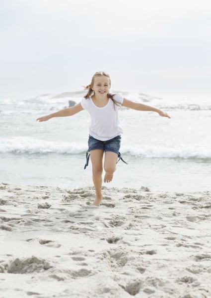 Portrait of girl (10-11) running on beach. Photo : Momentimages