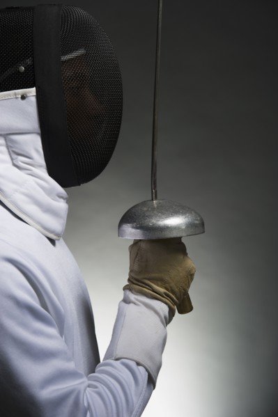 Studio portrait of fencer holding fencing foil.