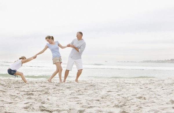 Girl (10-11) playing on beach with parents. Photo : Momentimages